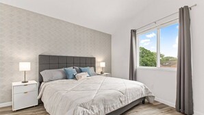 Ein Schlafzimmer mit Bett, Nachttischen und einem Fenster mit Vorhängen.