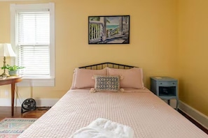 A bedroom with a bed, a bedside table, a nightstand, a lamp, and a window with blinds. - Historic German Village Home/A+ Downtown Columbus Location (Columbus)