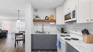 Una cocina moderna con armarios grises, encimera blanca y estufa integrada.