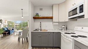 A modern kitchen with grey cabinets, a white stove, and a built-in microwave. - Concord C1 · Slice of the Good Life: Concord C1 (Peoria)