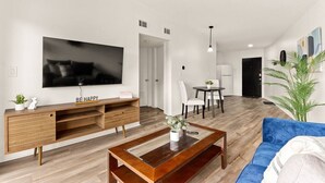 A modern living room with a flat-screen TV, wooden entertainment unit, and a blue sofa. - Concord C1 · Slice of the Good Life: Concord C1 (Peoria)