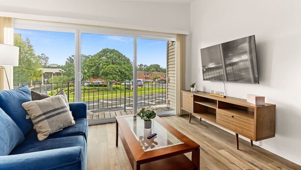 A modern living room with a blue sofa, a wooden coffee table, and a TV on the wall. - Concord C1 · Slice of the Good Life: Concord C1 (Peoria)
