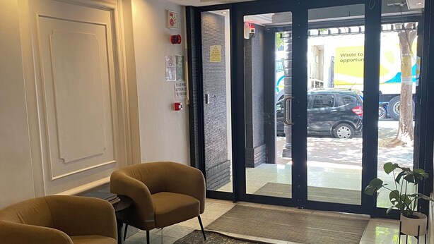 Zona de recepción de hotel con dos sillones, un tapete estampado y un amplio ventanal que da al exterior.