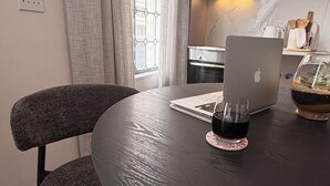 Una cocina moderna con una mesa de comedor redonda, una computadora portátil, una copa de vino tinto y una planta en maceta.