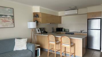 A compact kitchen with a central island, a sofa with a white cushion, and a lamp.