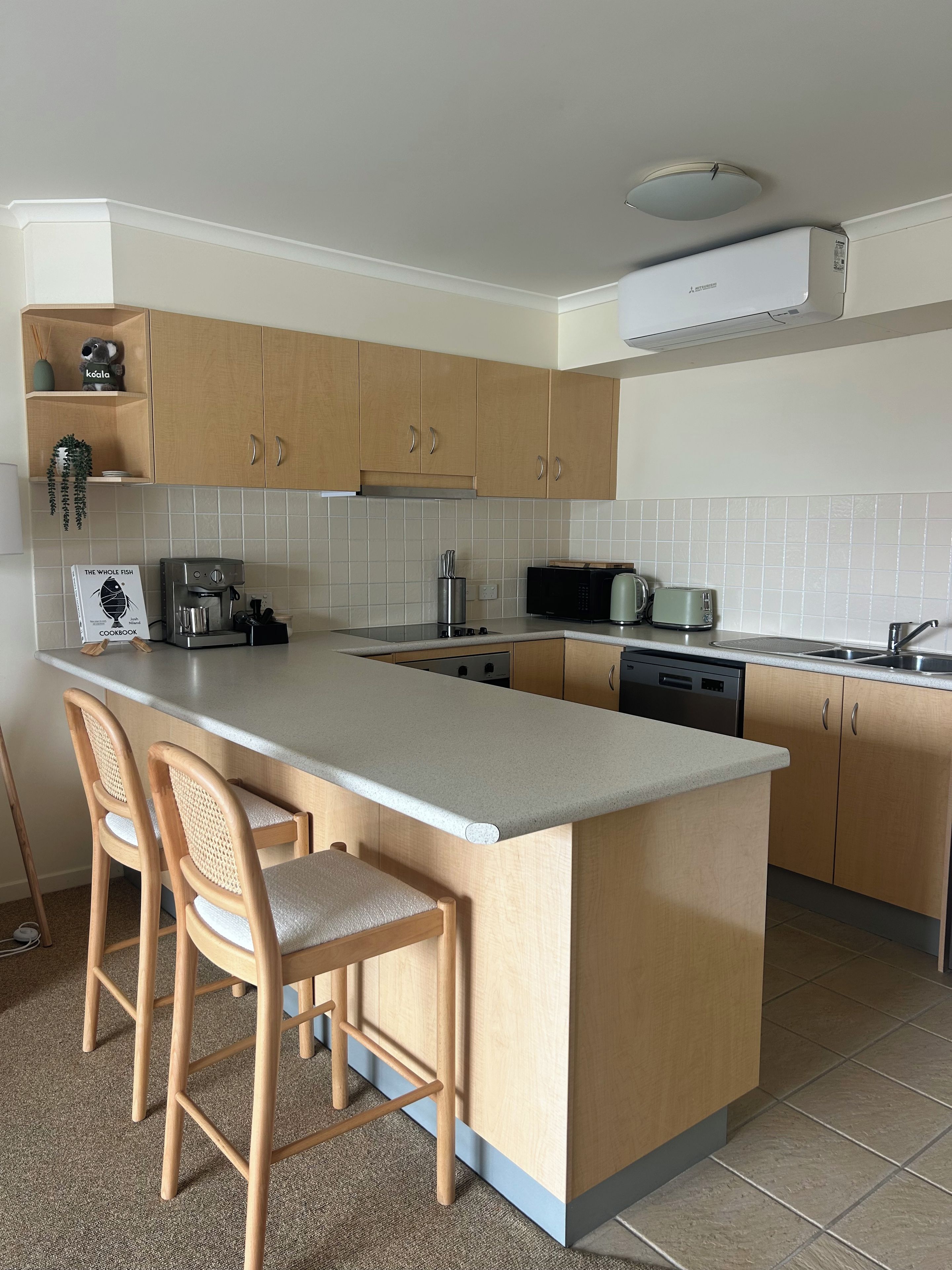 A modern kitchen with a central island, bar stools, a coffee machine, a microwave, and a toaster.