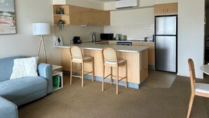 Eine kompakte Küche mit einer zentralen Kochinsel, einer Mikrowelle, einem Toaster und einem Kühlschrank.