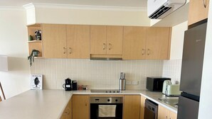 Eine moderne Küche mit Holzausbau, einem Edelstahlbackofen, einem eingebauten Geschirrspüler und einem schwarzen Kühlschrank.