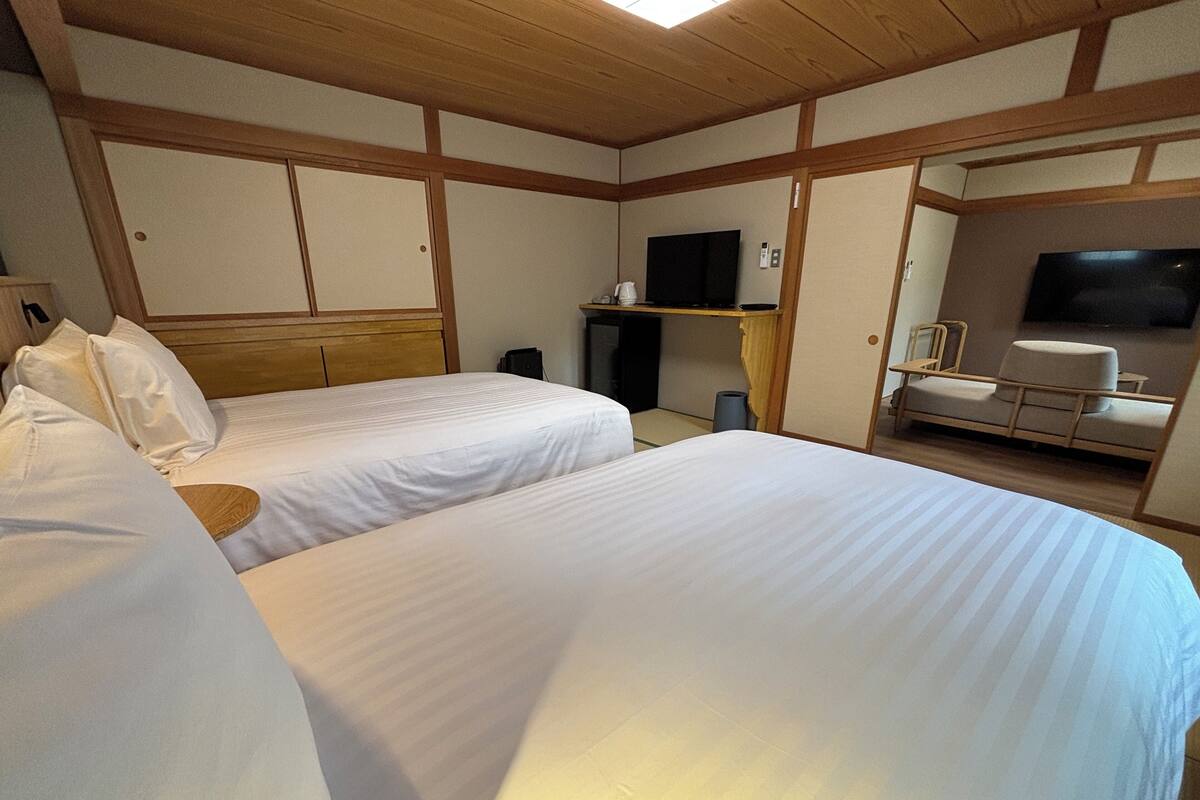 Una habitación de hotel con dos camas, televisión, una mesita y un sofá.