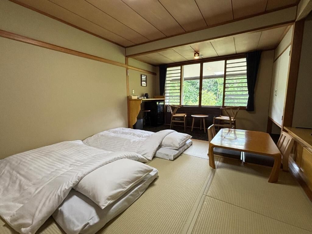 A room with two beds, a small table, and a desk with a chair.
