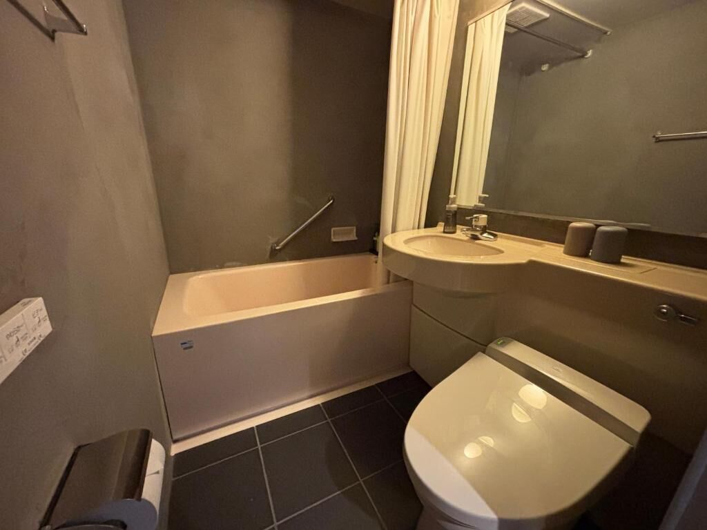 A bathroom with a bathtub, toilet, sink, and mirror.