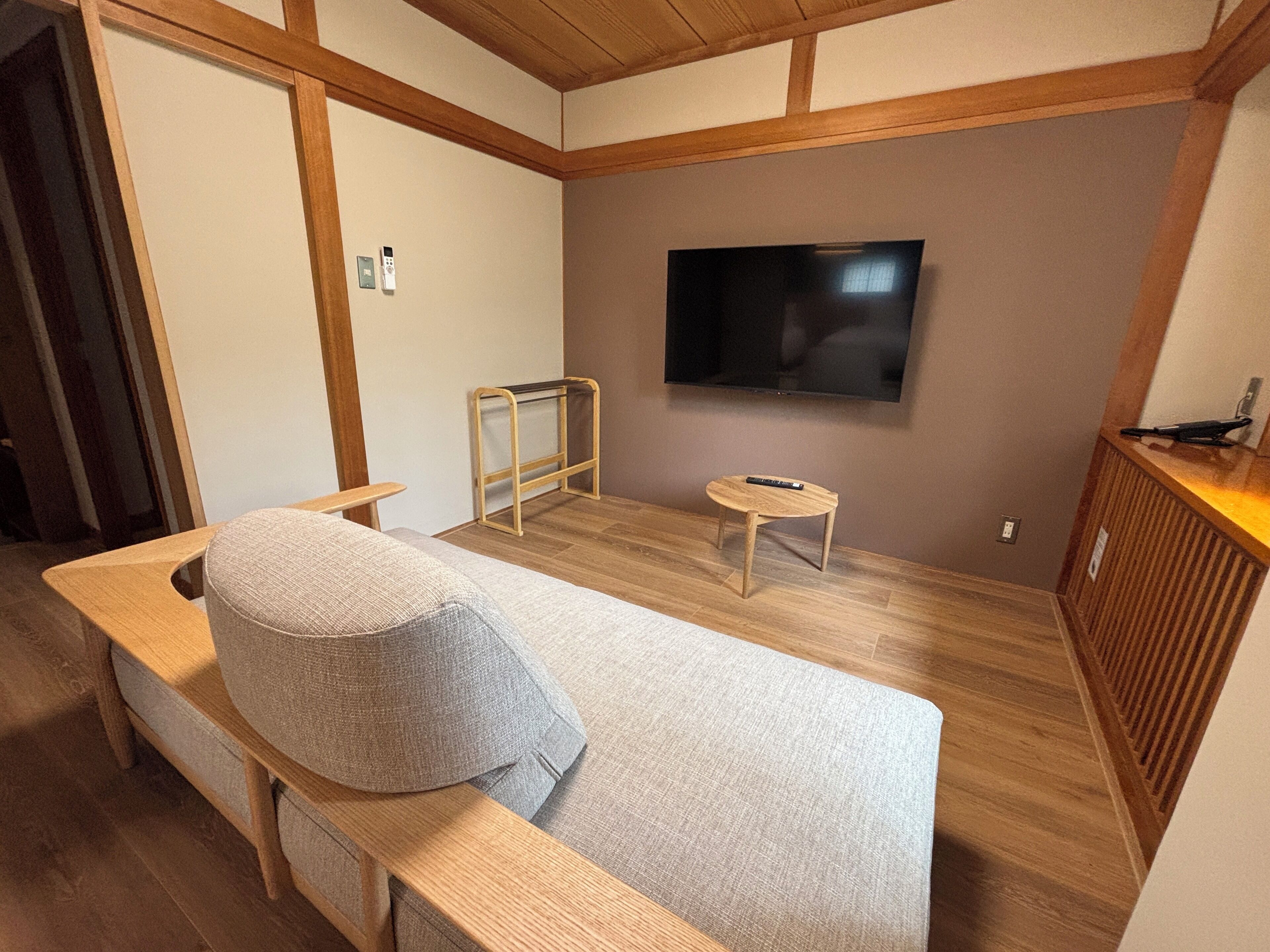 A modern room with a wooden bench, a small table, and a flat-screen TV mounted on the wall.
