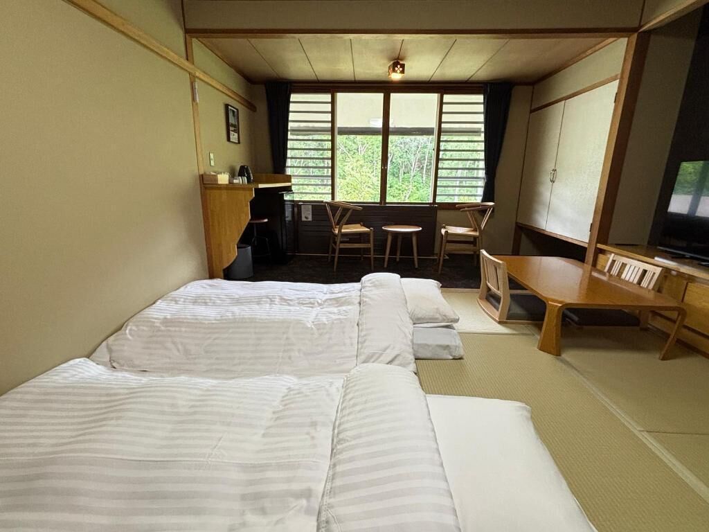 A room with two beds, a desk, a chair, and a television.