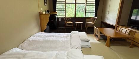 A room with two beds, a desk, a chair, and a television.