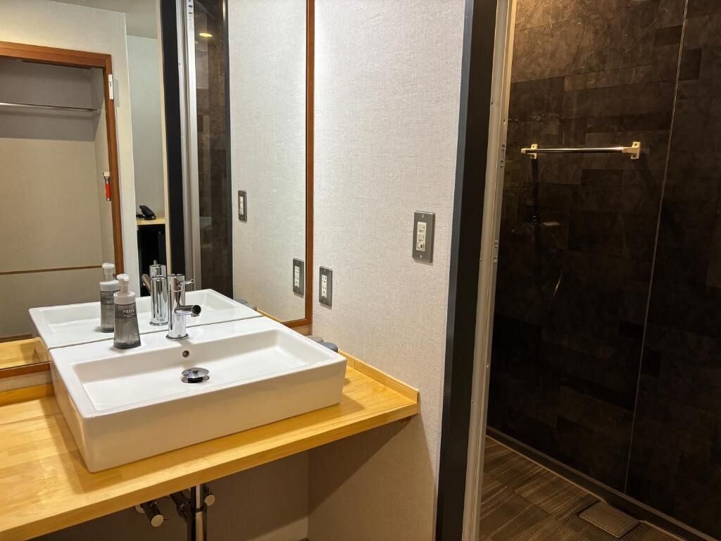 Une salle de bain avec un lavabo blanc, un miroir et un espace douche.
