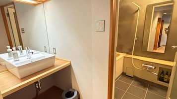 A modern bathroom with a large sink, mirror, and shower area.