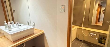 A modern bathroom with a large sink, mirror, and shower area.