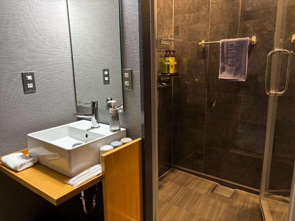 Une salle de bain moderne avec un grand lavabo, un miroir et un espace douche.