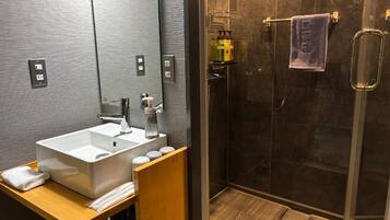 Une salle de bain moderne avec un grand lavabo, un miroir et un espace douche.