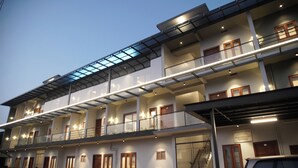 A multi-story hotel with balconies, a covered walkway, and a car parked in front. - Gentur Enclave  (Mananthavady)