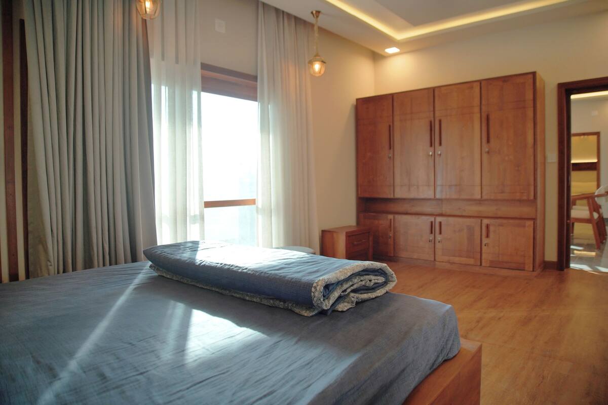 Un dormitorio con cama, armario de madera y ventana con cortinas.