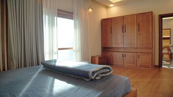 A bedroom with a bed, wooden wardrobe, and a window with curtains.