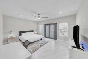 Ein modernes Schlafzimmer mit Bett, Schreibtisch, Stuhl und Fernseher.