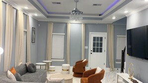 A modern living room with a sofa, armchairs, a coffee table, and a TV. - Elegant Modern Retreat • Sleeps 6 • Near NRG (Houston)