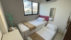 A hotel room with two beds, a window with a city view, a green coat rack, and a mirror on the wall. - Ocean View on the 20th Floor | Rooftop with Jacuzzi | 1 Block from the Beach | (Maceió)