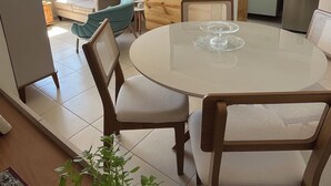 A modern kitchen with a built-in oven, a refrigerator, and a wooden countertop. There is a dining area with a round table and chairs. - Ocean View on the 20th Floor | Rooftop with Jacuzzi | 1 Block from the Beach | (Maceió)