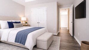 Une chambre à coucher comprenant un lit, une table de chevet, une lampe et un téléviseur fixé au mur.