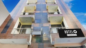 A modern hotel building with a prominent sign reading "HOTEL Company Serviced". - Super Hotel O Sheetla Colony (Gurugram)