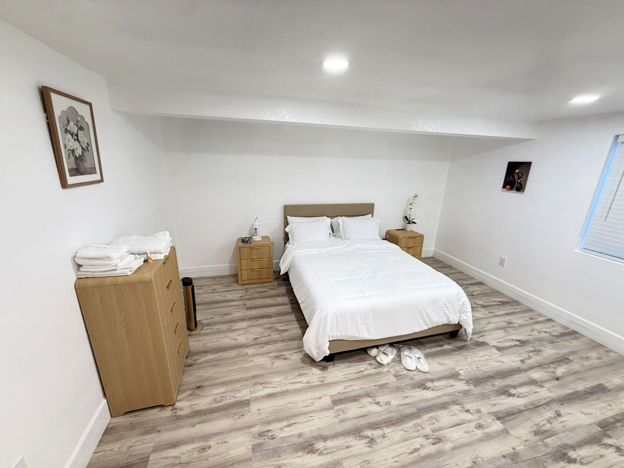 Een slaapkamer met een bed, twee nachtkastjes, een kledingkast en een raam.