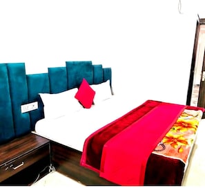 A bed with a blue headboard, white bedding, and a red pillow. - Hotel Ravintam (Mathura)