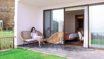 A balcony with wicker chairs, a person reading a magazine, and a view of the interior.
