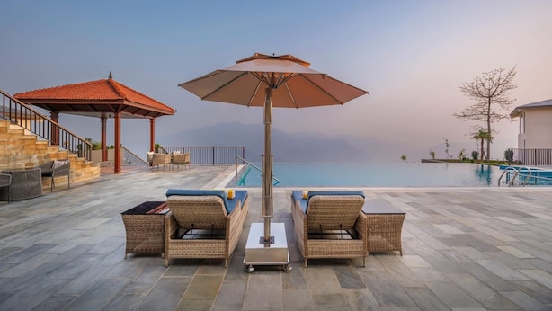 Ein Poolbereich mit Korbmöbeln, einem Pavillon und Blick auf das Meer.