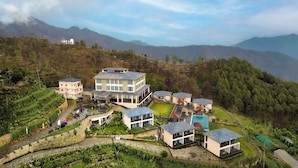 Ein modernes Hotel mit mehreren Gebäuden, terrassenförmigen Gärten und einer Bergkulisse.