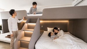 Un dormitorio moderno con escaleras empotradas, una cama y un pequeño rincón de descanso.