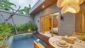 A modern outdoor pool area with a wooden deck, a dining table set with plates and glasses, and a large woven light fixture. - Villa Umahera - Canggu (Canggu)