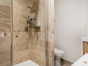 A bathroom with a glass-enclosed shower, a white toilet, and a sink with a wooden cabinet. - The Big Blue! Between sea and mountains (Saint-Cyprien)