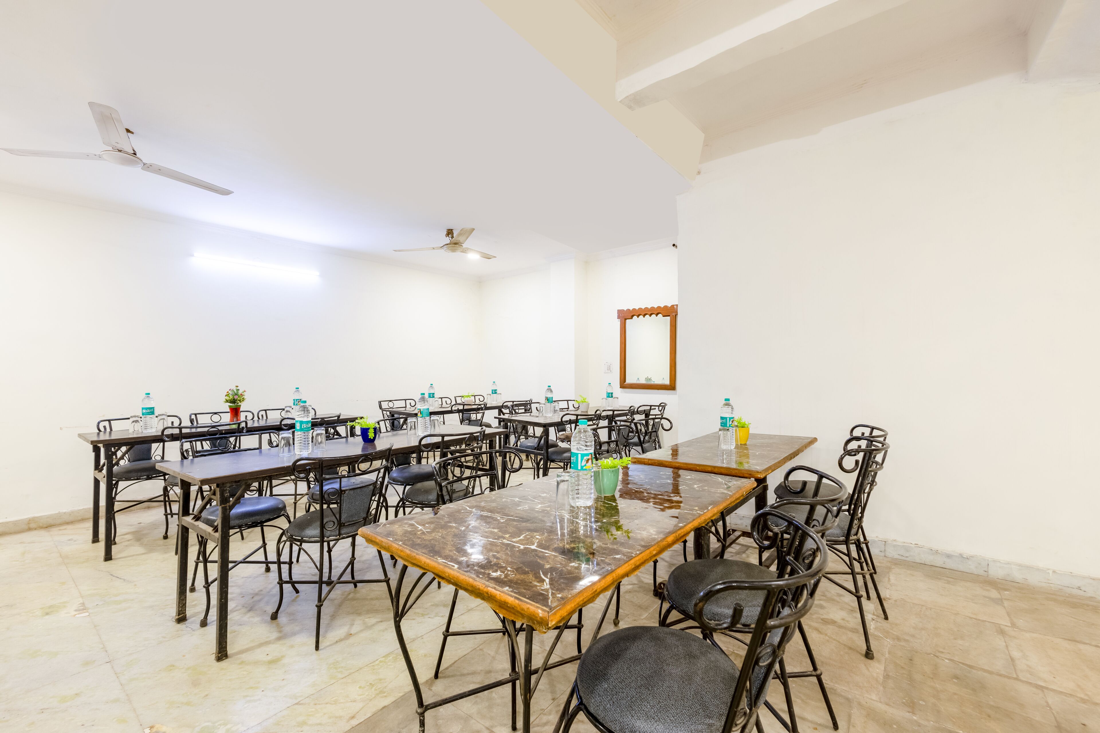 A conference room with multiple tables and chairs, ceiling fans, and a mirror on the wall.