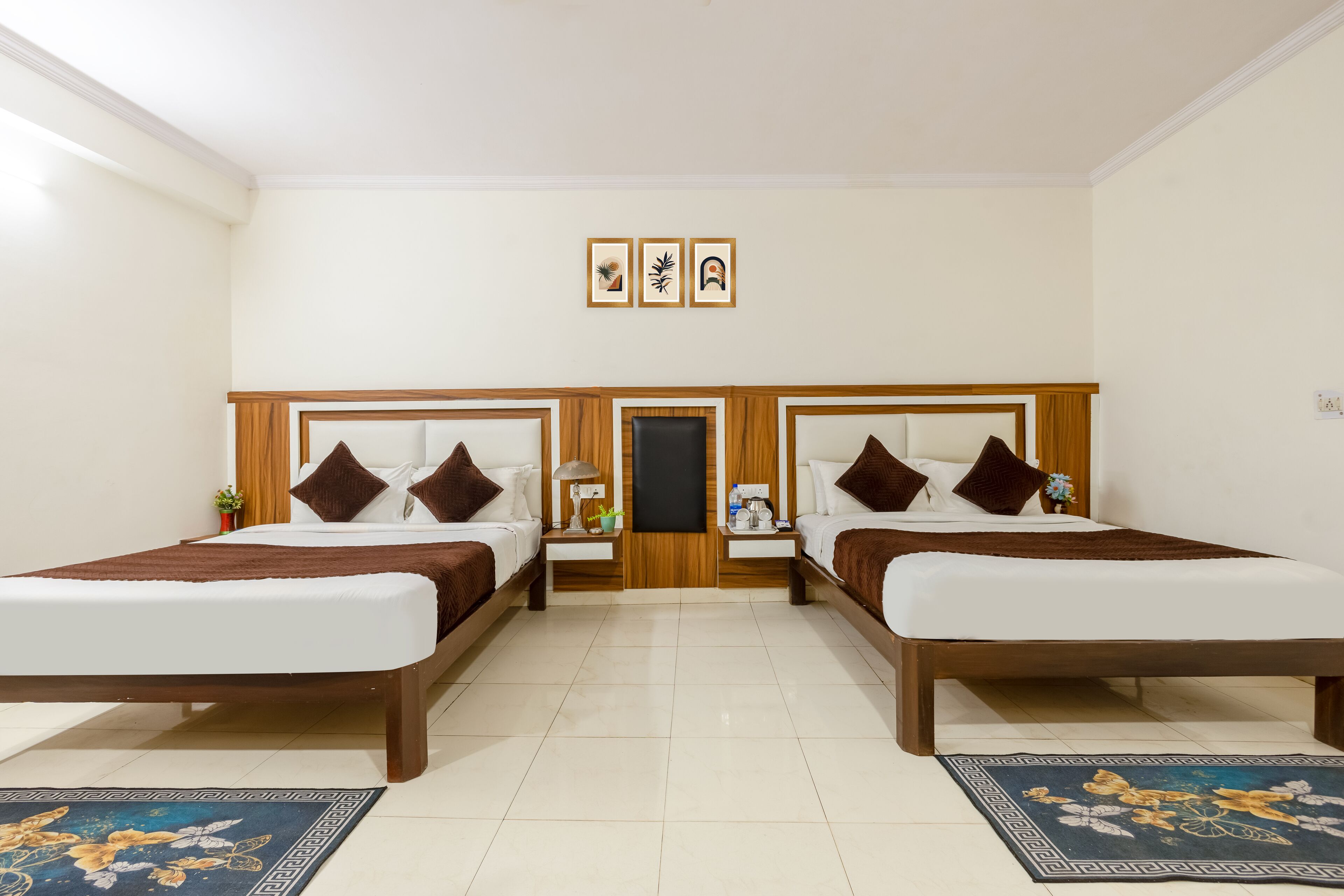 A hotel room with two single beds, a wooden headboard, a small table, and a nightstand.