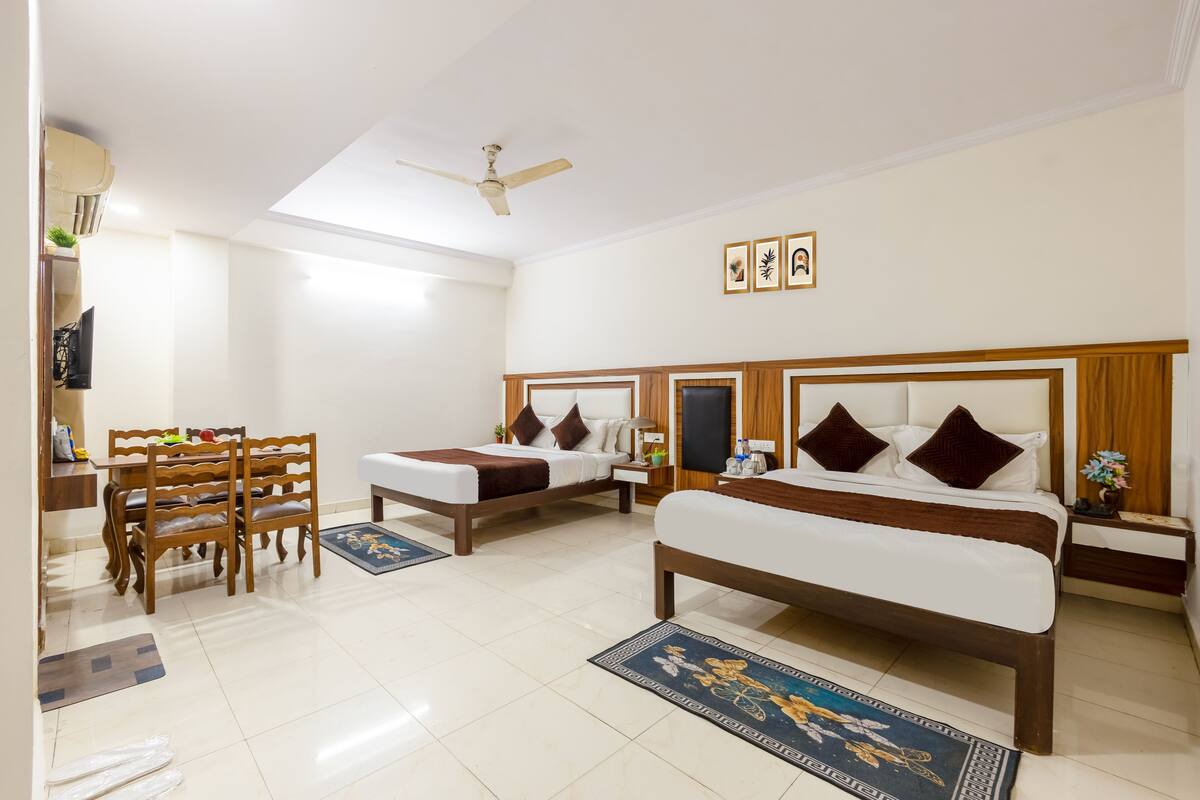 Quarto de hotel com duas camas, uma mesa de jantar e um ventilador de teto.