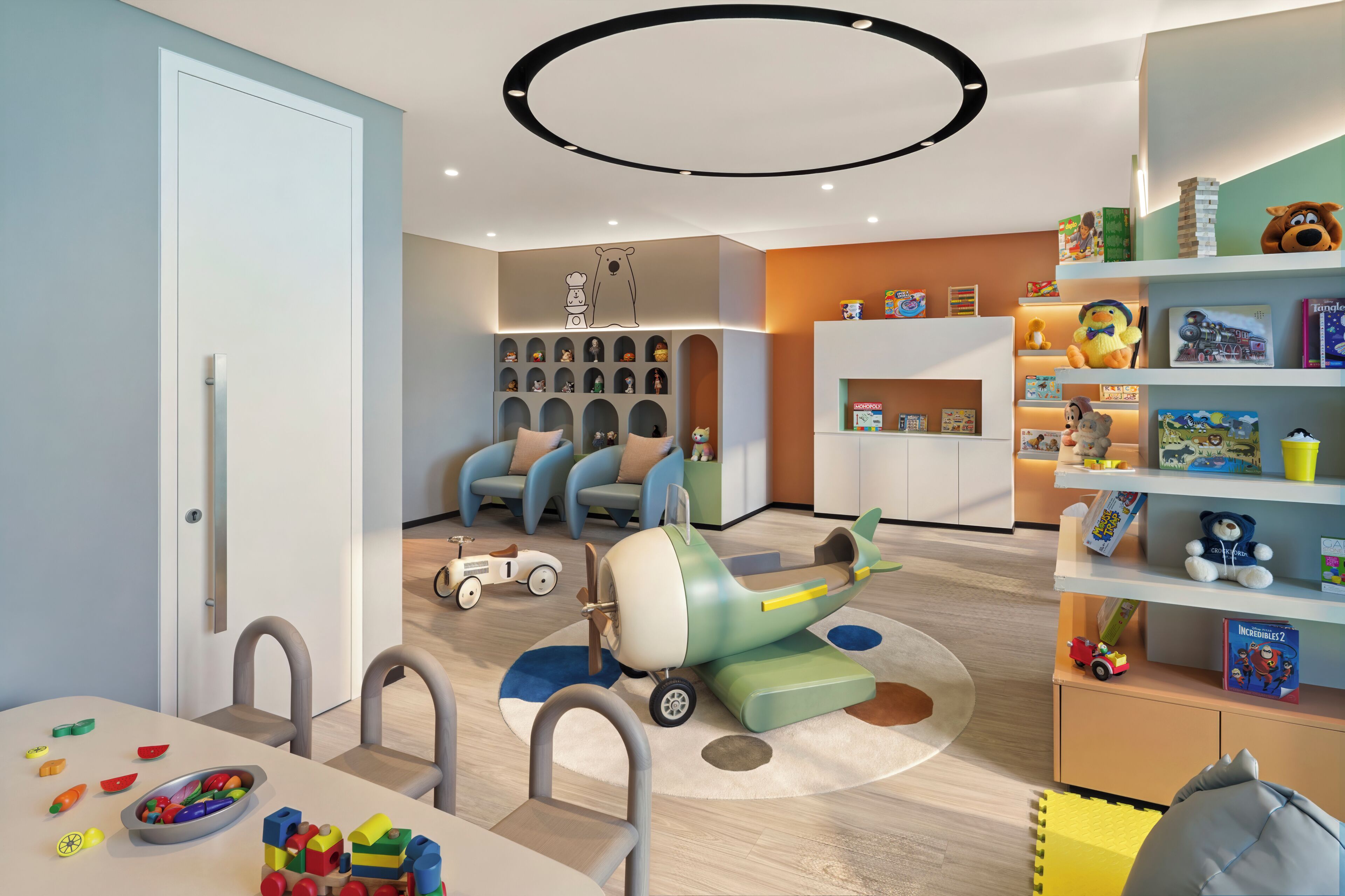 A modern children's playroom with a dining area, toys, and educational materials.