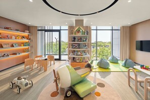 A modern children's playroom with a large window, a bookshelf, and a play area with toys and seating. - Vida Aljada (Sharjah)