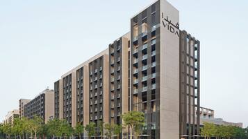 A modern multi-story building with a prominent 'VIDA' sign, featuring a grid of balconies and a flat roofline.