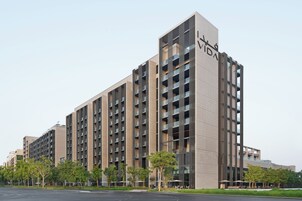 Un edificio moderno de varios pisos con un llamativo letrero 'VIDA', que presenta una serie de balcones y una línea de techo plana.