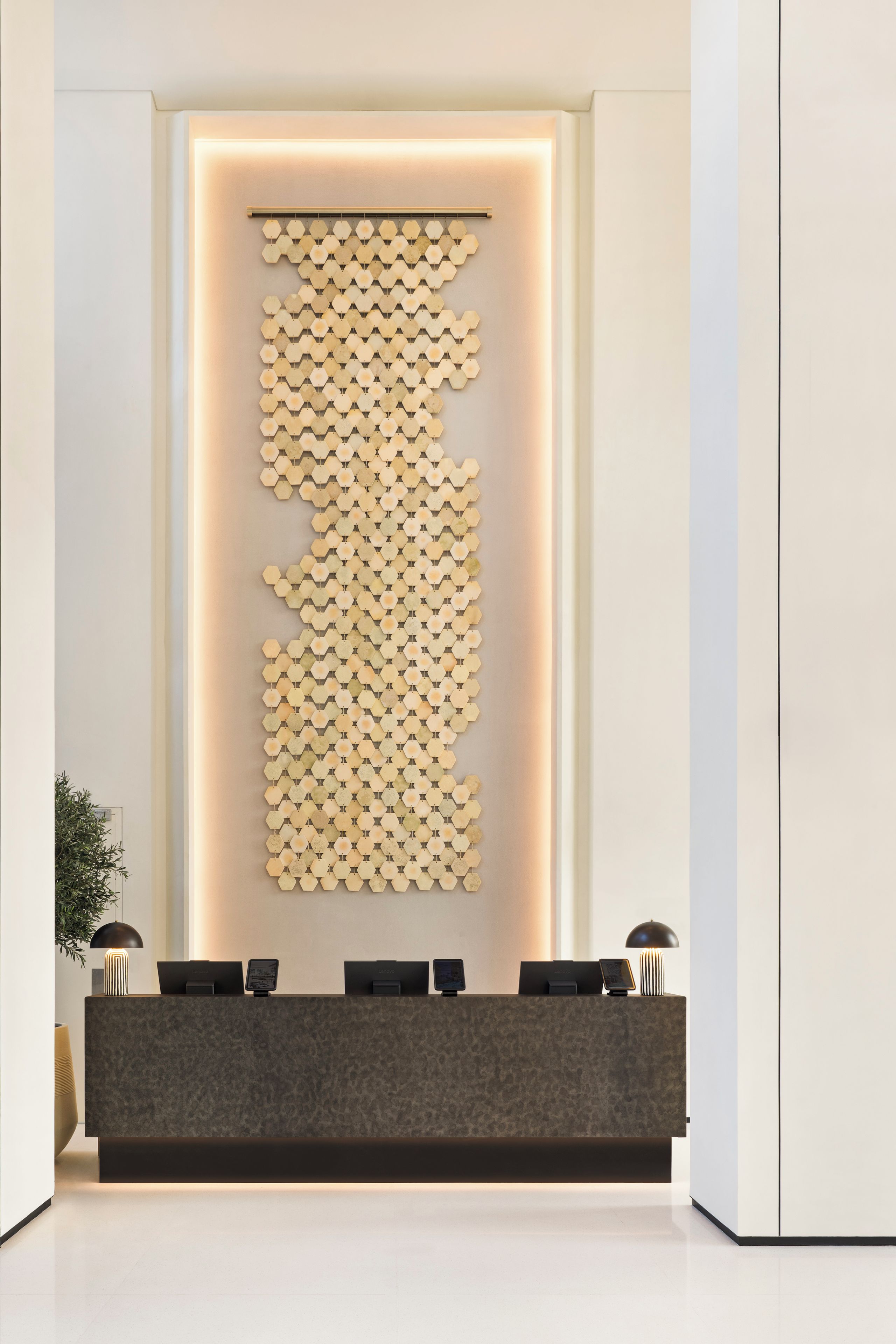 Un comptoir d’accueil au design moderne, agrémenté d’un motif hexagonal mural et caractérisé par une esthétique minimaliste.