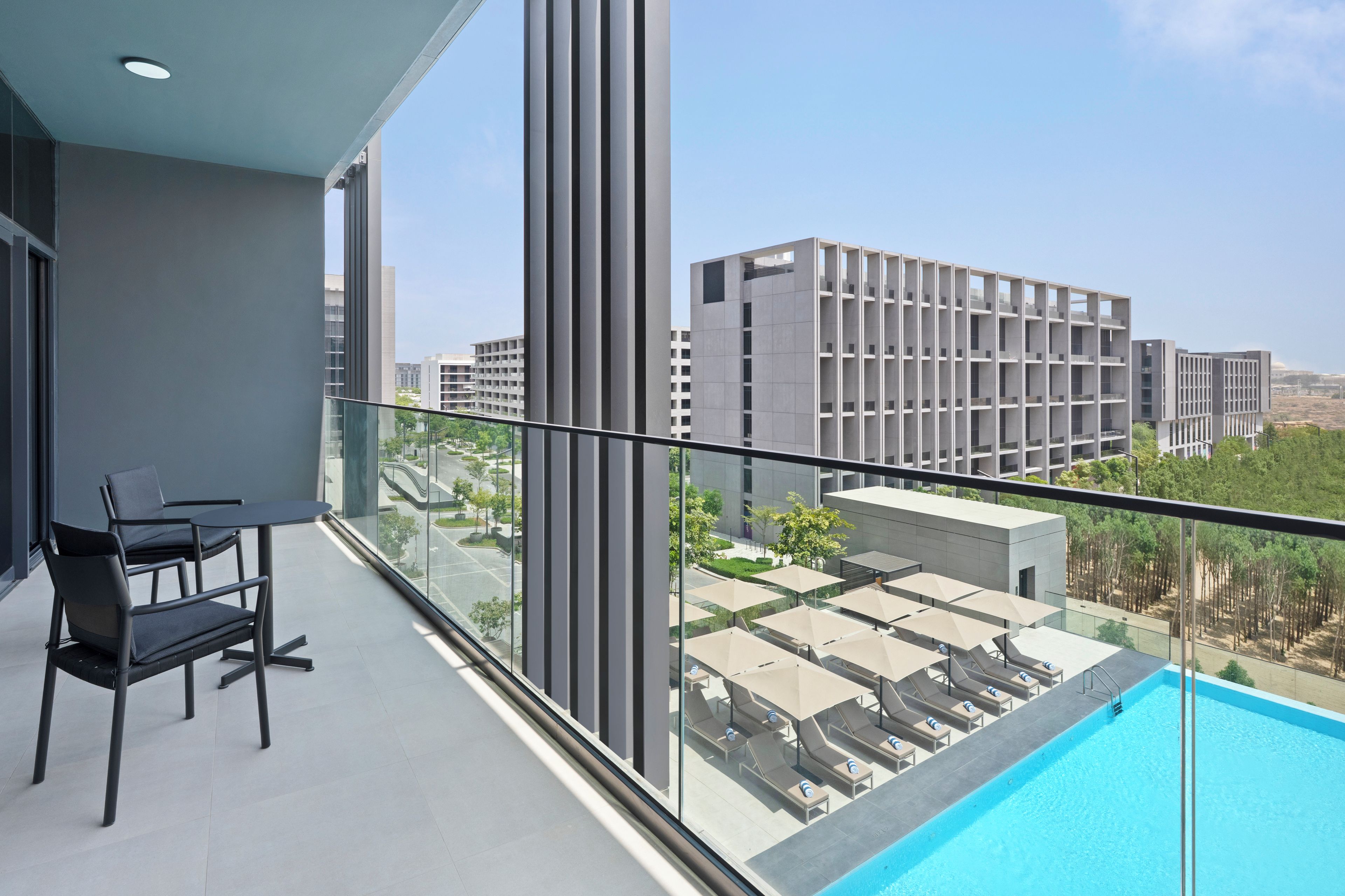 Un balcón con piscina, una mesa con sillas y vistas de edificios circundantes.