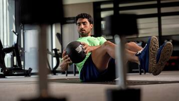 Uma pessoa fazendo exercício com uma bola medicinal em uma academia.